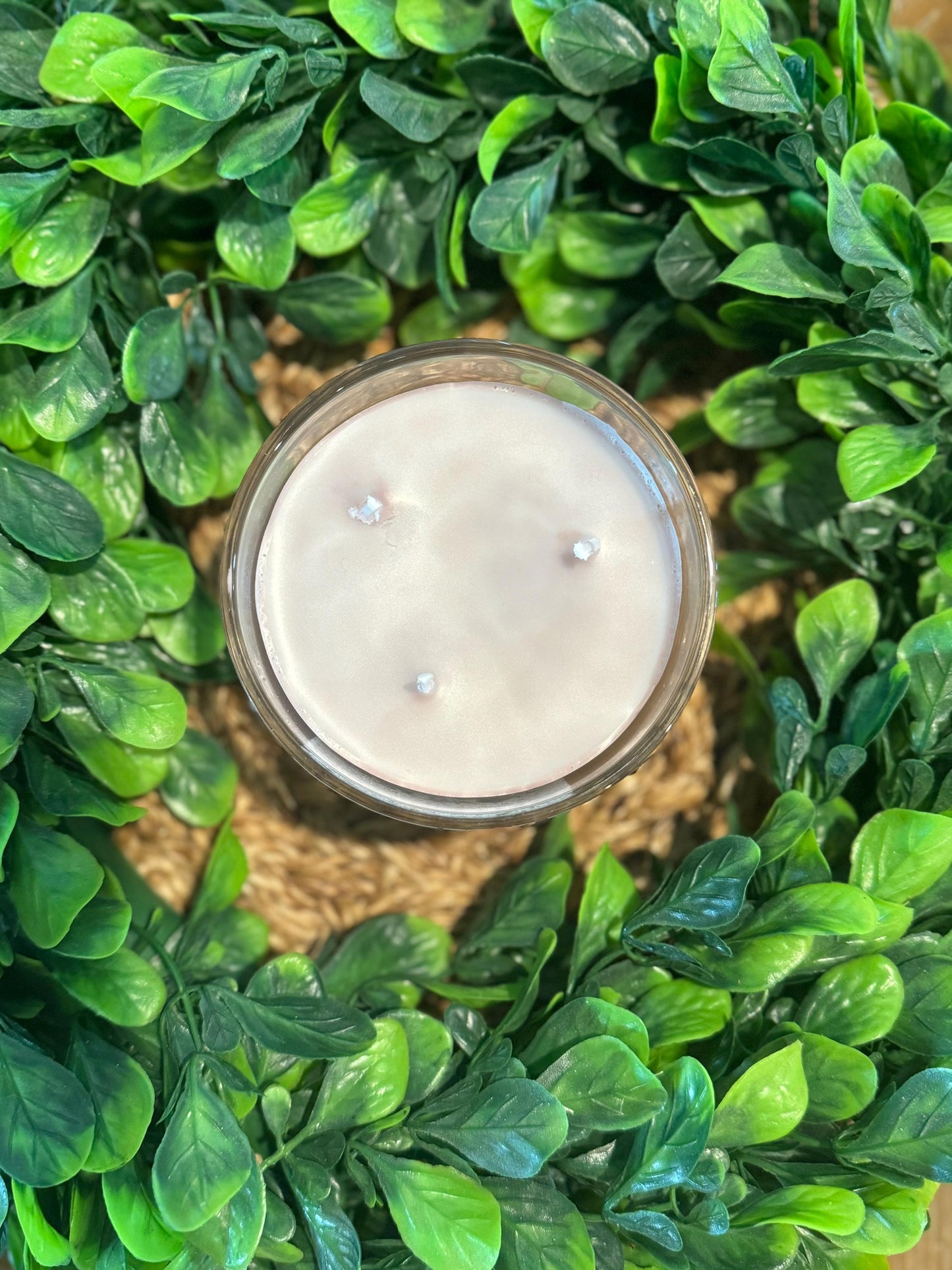 a candle surrounded by green leaves