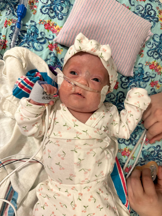 a baby in a hospital gown is being held by a nurse