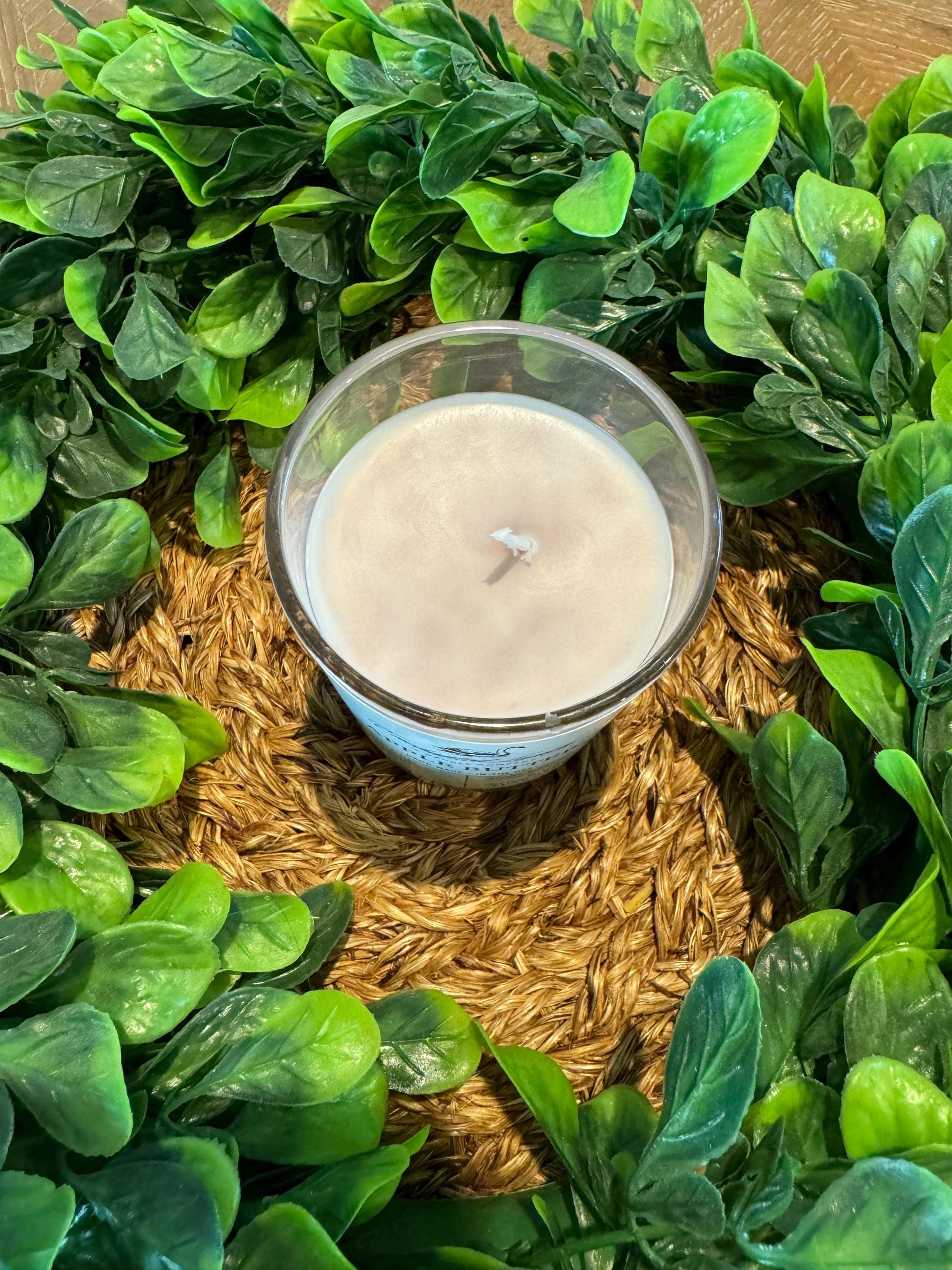 a candle sitting on top of a wooden table surrounded by green leaves