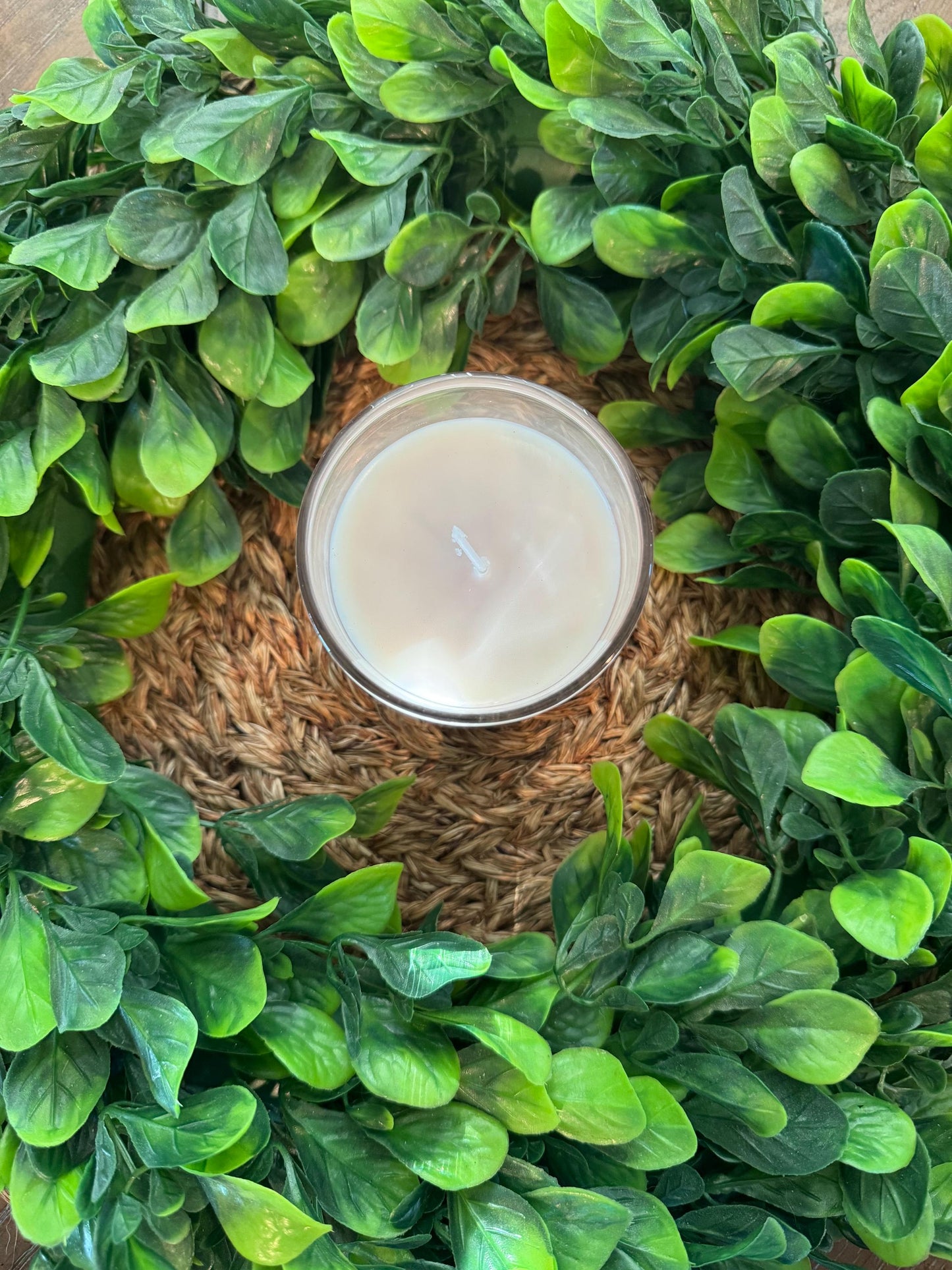 a candle surrounded by green leaves on a table
