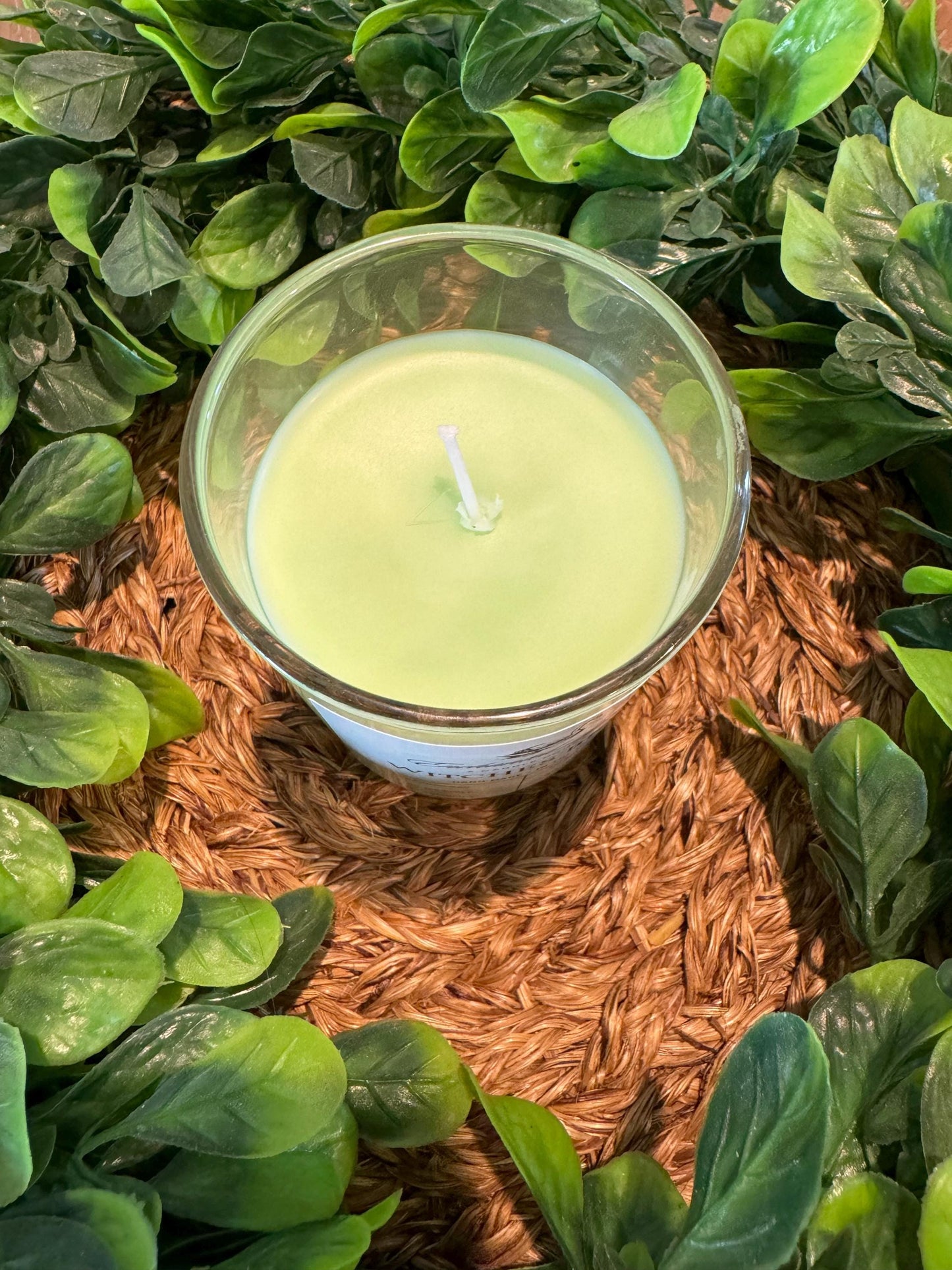 a candle surrounded by green leaves