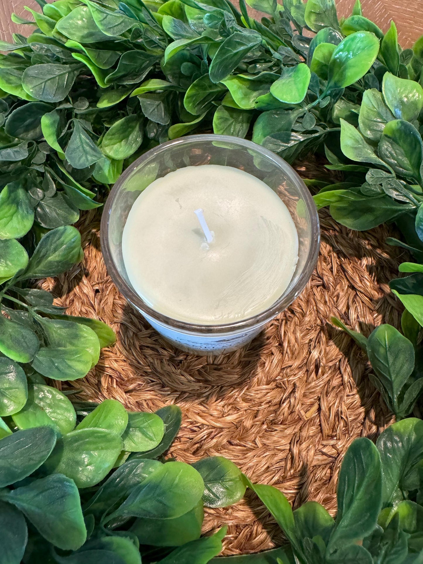 a candle sitting on a table surrounded by green leaves